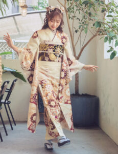 ベージュ系のニュアンスカラーに、身頃を迎えた梅や牡丹、菊など吉祥の花たちの麗しき競演。躍動感あふれる流水文様も慶びを伝えるよう。